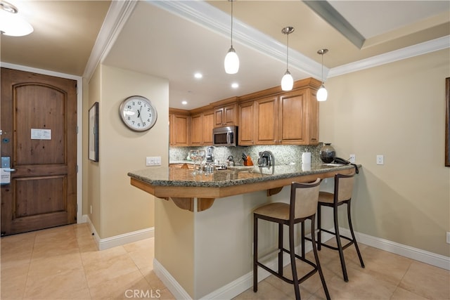 2727 Shell Beach Rd Unit 219, Pismo Beach, CA 93449 - kitchen with stainless steel microwave, backsplash, a breakfast bar area, brown cabinetry, and dark stone countertops