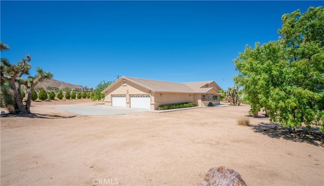 8920 Del Monte Ave, Yucca Valley, CA 92284 - view of front of property with driveway, an attached garage, and stucco siding