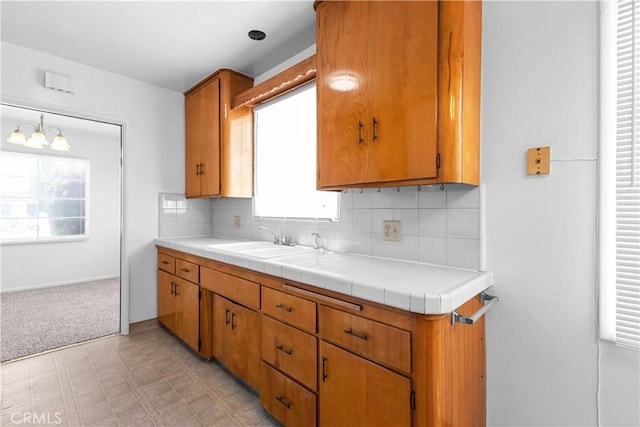1256 Windsor Dr, San Bernardino, CA 92404 - kitchen featuring backsplash, light flooring, brown cabinets, and a chandelier