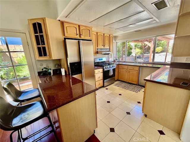 10116 Viking Ave, Northridge, CA 91324 - kitchen with stainless steel appliances, under cabinet range hood, a peninsula, light tile patterned floors, and a breakfast bar area