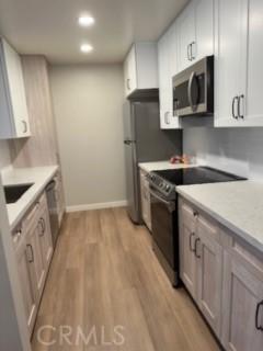 25715 Hogan Dr Unit B1, Valencia, CA 91355 - kitchen featuring stainless steel appliances, light wood finished floors, light countertops, recessed lighting, and white cabinetry