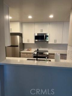 25715 Hogan Dr Unit B1, Valencia, CA 91355 - kitchen with appliances with stainless steel finishes, a peninsula, recessed lighting, white cabinetry, and light countertops