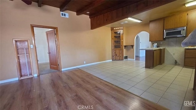 625 Cedar Ave, Wasco, CA 93280 - kitchen featuring stainless steel microwave, open floor plan, light countertops, tasteful backsplash, and light wood-type flooring