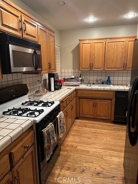 4807 Beck Ave Unit 4, Valley Village, CA 91601 - kitchen with gas range, stainless steel microwave, tile countertops, tasteful backsplash, and brown cabinets