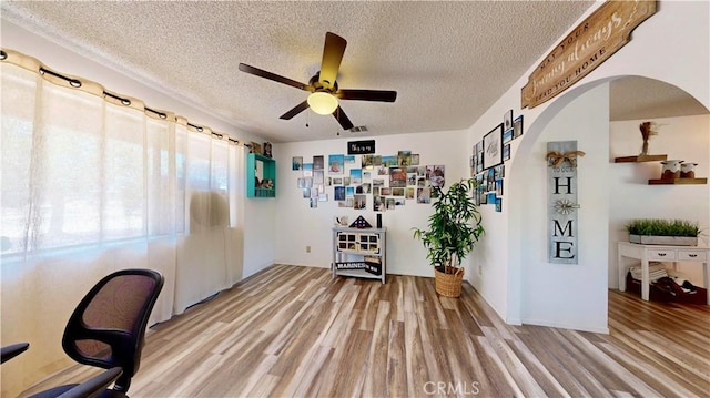 15233 Olive St, Hesperia, CA 92345 - spare room featuring light wood-style flooring, a ceiling fan, arched walkways, and a textured ceiling