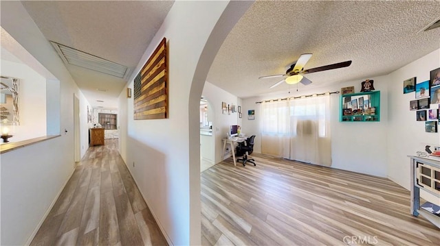15233 Olive St, Hesperia, CA 92345 - hall with light wood-style floors, arched walkways, a desk, and a textured ceiling