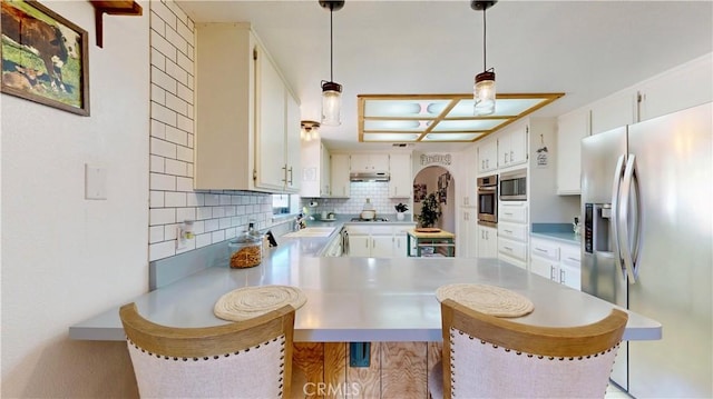 15233 Olive St, Hesperia, CA 92345 - kitchen with stainless steel appliances, tasteful backsplash, a peninsula, under cabinet range hood, and light countertops