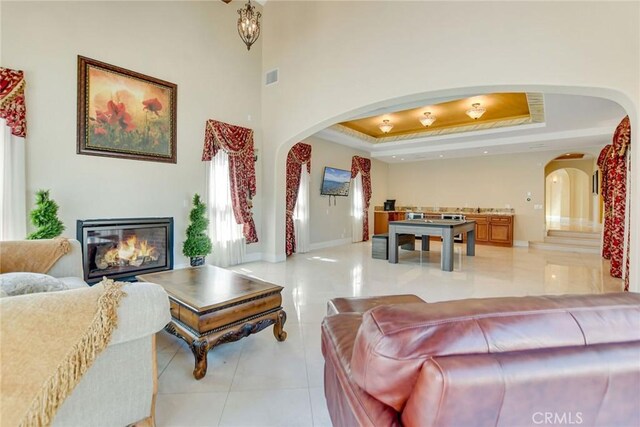 462 Pomello Dr, Claremont, CA 91711 - living room featuring arched walkways, a raised ceiling, light tile patterned flooring, and a glass covered fireplace