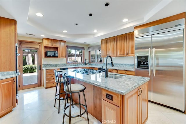 462 Pomello Dr, Claremont, CA 91711 - kitchen with stainless steel appliances, a center island with sink, light stone counters, a breakfast bar area, and light tile patterned floors