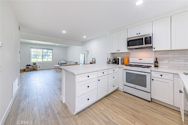 68 Timber Run Unit 45, Irvine, CA 92614 - kitchen featuring stainless steel microwave, white gas range, a peninsula, open floor plan, and light wood-style flooring
