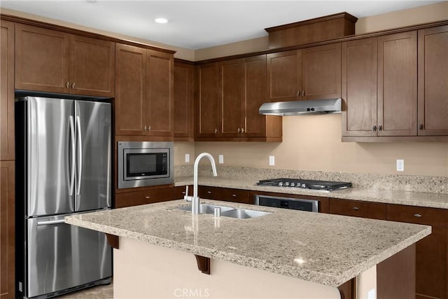 403 Sevilla Dr, Brea, CA 92823 - kitchen with stainless steel appliances, under cabinet range hood, light stone counters, a kitchen island with sink, and a kitchen breakfast bar