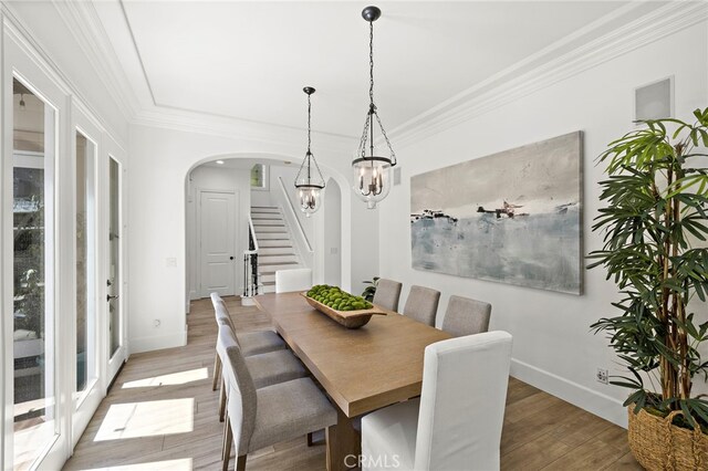 19 Dennis Ln, Ladera Ranch, CA 92694 - dining space with arched walkways, stairway, a chandelier, light wood-type flooring, and crown molding