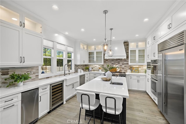 19 Dennis Ln, Ladera Ranch, CA 92694 - kitchen with beverage cooler, stainless steel appliances, custom range hood, white cabinets, and hanging light fixtures