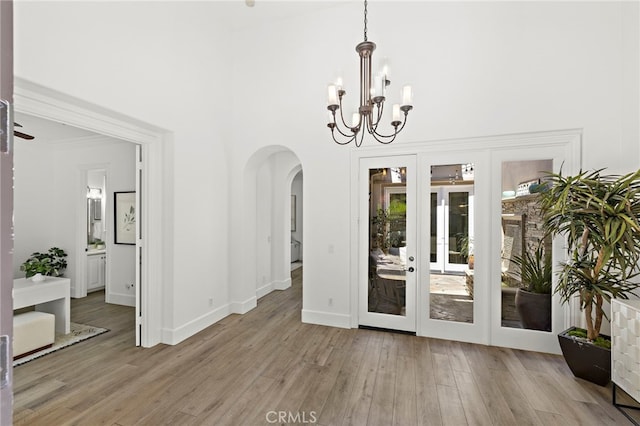 19 Dennis Ln, Ladera Ranch, CA 92694 - unfurnished dining area featuring arched walkways, a chandelier, wood finished floors, french doors, and a high ceiling