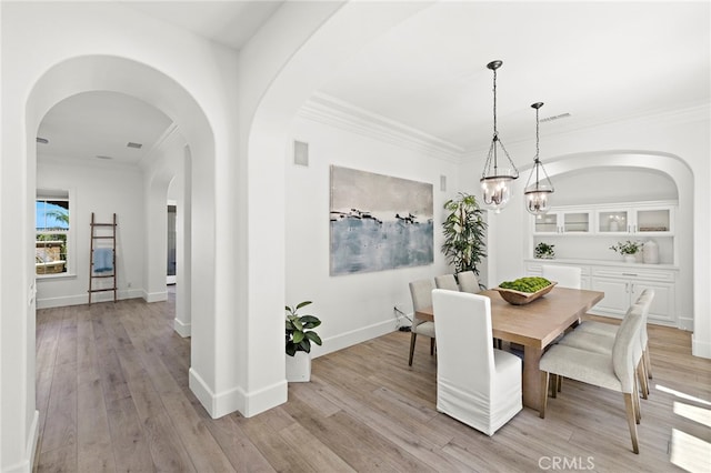 19 Dennis Ln, Ladera Ranch, CA 92694 - dining space featuring arched walkways, crown molding, light wood finished floors, and a chandelier
