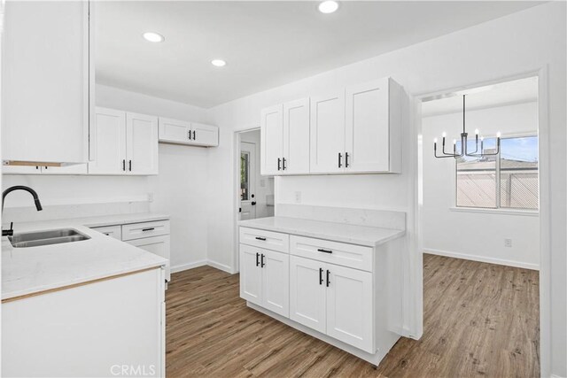 1920 Doolittle Ave, Bakersfield, CA 93304 - kitchen with light wood-type flooring, white cabinets, recessed lighting, a chandelier, and light stone counters