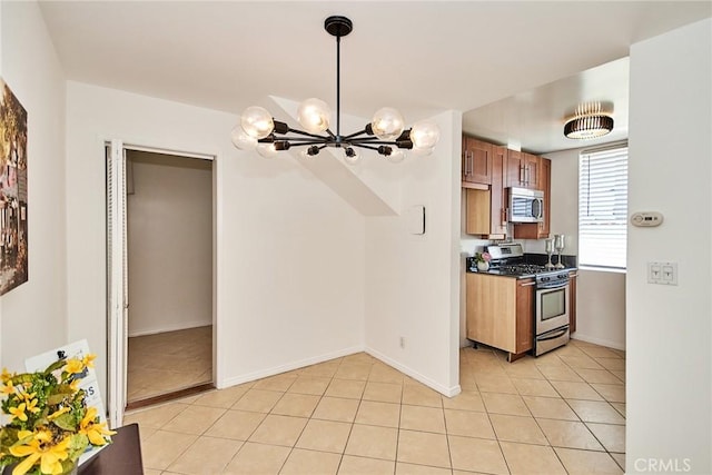 856 N Van Ness Ave Unit 3, Los Angeles, CA 90038 - kitchen with stainless steel appliances, light tile patterned flooring, a chandelier, and brown cabinets