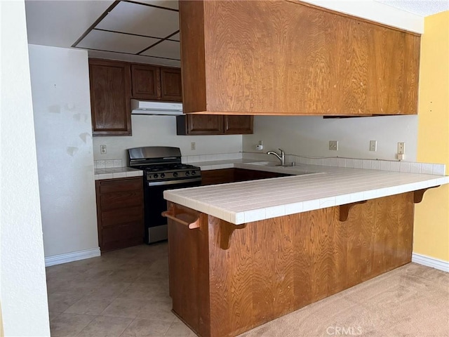 640 Juniper Way, La Habra, CA 90631 - kitchen with stainless steel gas range, exhaust hood, a peninsula, a breakfast bar area, and brown cabinetry