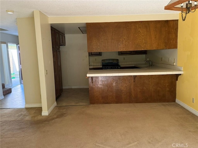 640 Juniper Way, La Habra, CA 90631 - kitchen featuring light colored carpet, tile countertops, a peninsula, range, and a kitchen breakfast bar