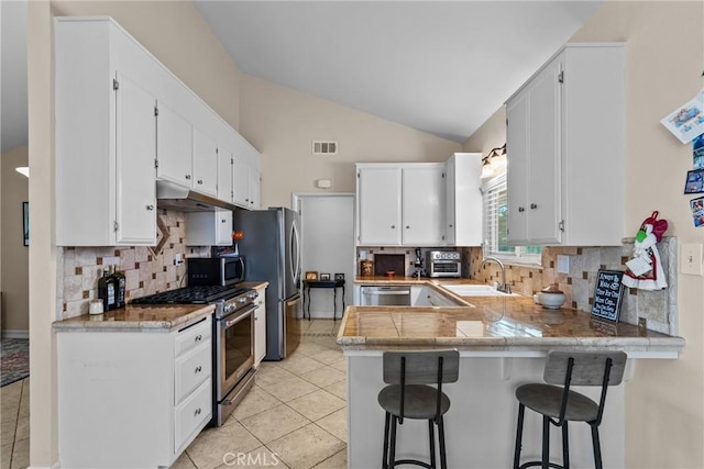27124 Cabrera Ave, Saugus, CA 91350 - kitchen with stainless steel appliances, a peninsula, white cabinets, light tile patterned floors, and vaulted ceiling