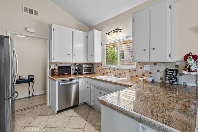 27124 Cabrera Ave, Saugus, CA 91350 - kitchen featuring stainless steel appliances, backsplash, tile countertops, white cabinetry, and lofted ceiling
