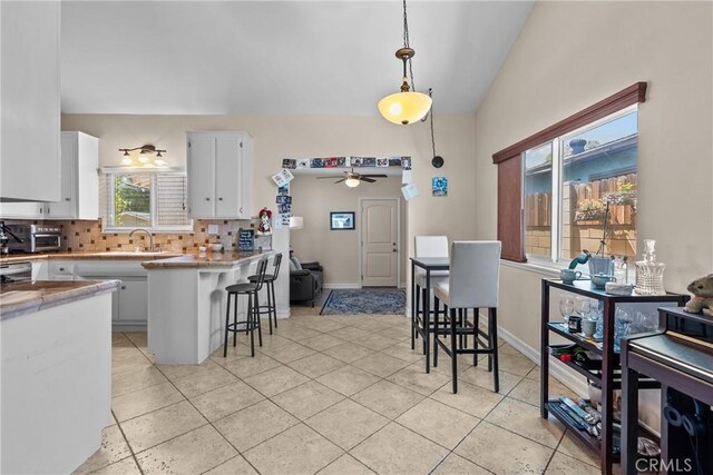 27124 Cabrera Ave, Saugus, CA 91350 - kitchen with tasteful backsplash, a ceiling fan, white cabinets, a breakfast bar, and hanging light fixtures