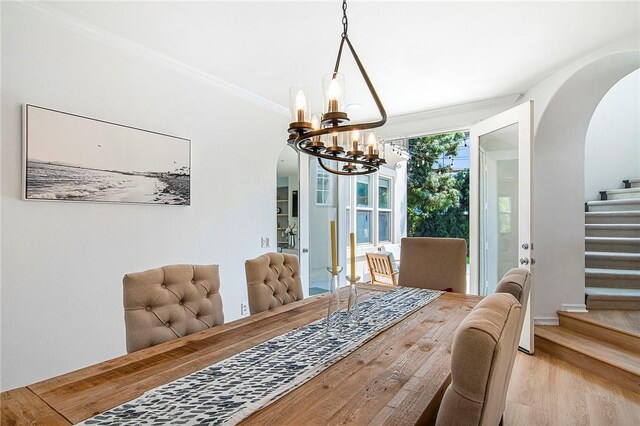 3417 Kildare Ct, Burbank, CA 91504 - dining space featuring arched walkways, a chandelier, light wood-style floors, stairs, and crown molding