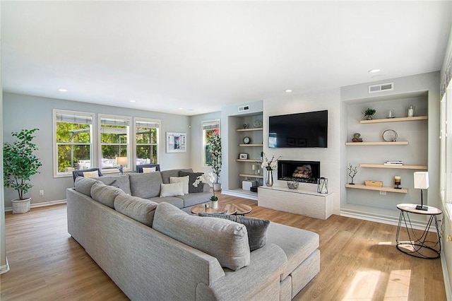 3417 Kildare Ct, Burbank, CA 91504 - living room with a fireplace with raised hearth, light wood-style flooring, built in features, and recessed lighting