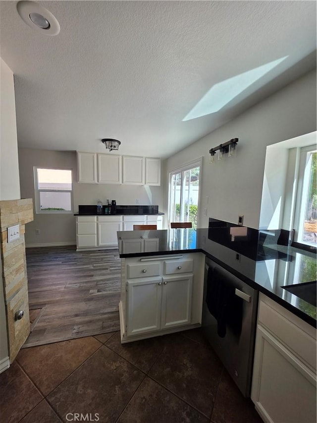 29390 Crest View Ln, Highland, CA 92346 - kitchen featuring dark countertops, white cabinetry, a skylight, healthy amount of natural light, and a textured ceiling