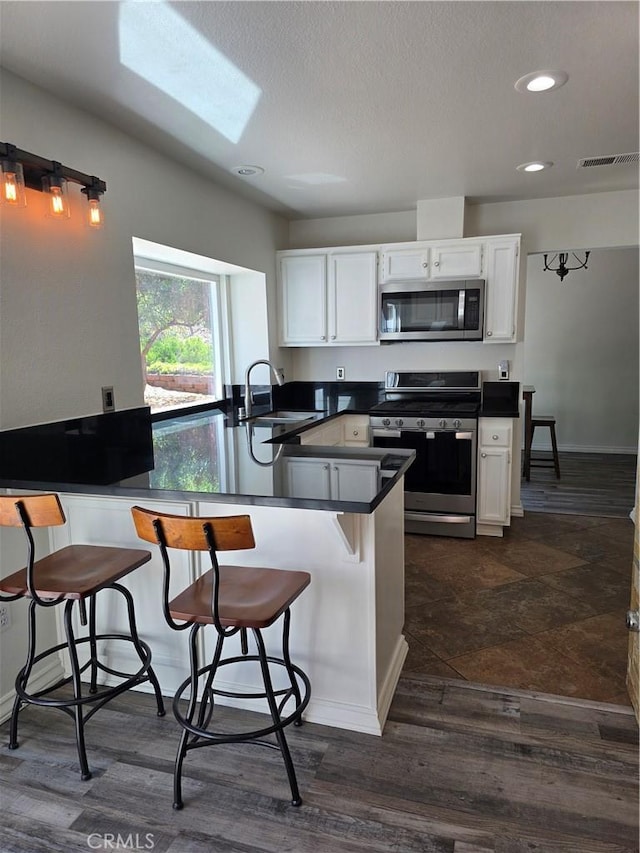 29390 Crest View Ln, Highland, CA 92346 - kitchen with stainless steel appliances, a peninsula, recessed lighting, dark countertops, and white cabinets