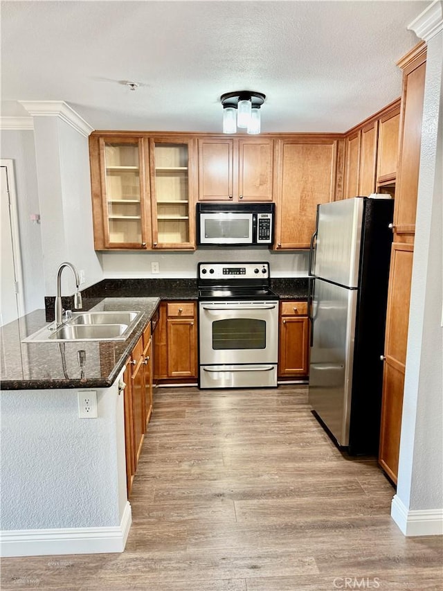 1025 La Terraza Cir Unit 204, Corona, CA 92879 - kitchen featuring stainless steel appliances, a peninsula, light wood-style flooring, glass insert cabinets, and dark stone countertops