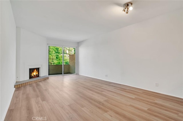 3480 Barham Blvd Unit 215, Los Angeles, CA 90068 - unfurnished living room featuring light wood-type flooring and a lit fireplace