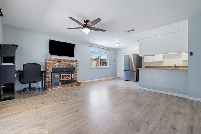 3318 Stanford Ave, Clovis, CA 93611 - living area with ceiling fan, light wood-style floors, and a wood stove