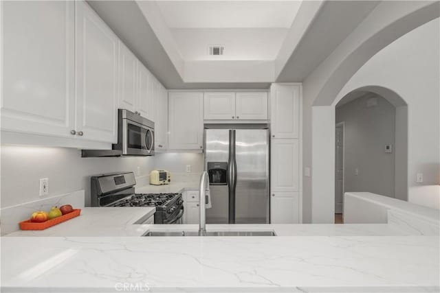 8 Diamant Way, Aliso Viejo, CA 92656 - kitchen with stainless steel appliances, arched walkways, light stone countertops, and white cabinets