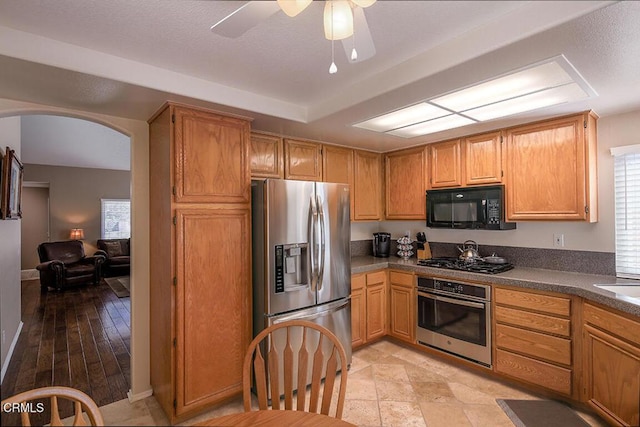 20325 Tamara Pl, Santa Clarita, CA 91350 - kitchen with stainless steel appliances, arched walkways, dark countertops, and a ceiling fan