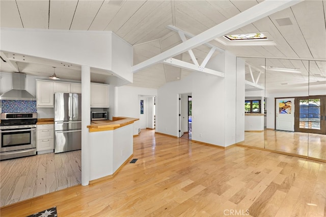 490 Agate, Laguna Beach, CA 92651 - kitchen featuring wall chimney exhaust hood, appliances with stainless steel finishes, open floor plan, light wood-style flooring, and white cabinetry