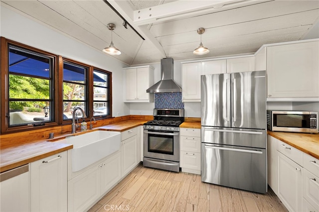 490 Agate, Laguna Beach, CA 92651 - kitchen featuring wooden counters, appliances with stainless steel finishes, wall chimney range hood, white cabinets, and light wood-style floors