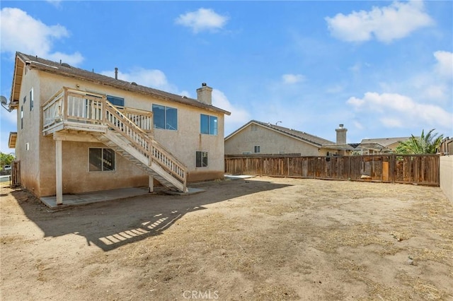 9304 Palo Verde Dr, Hesperia, CA 92344 - back of house with a fenced backyard, stucco siding, a chimney, and stairway