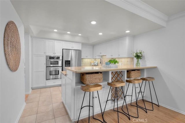 1201 S Catalina Ave Unit 3A, Redondo Beach, CA 90277 - kitchen featuring stainless steel appliances, white cabinetry, backsplash, a breakfast bar, and a peninsula