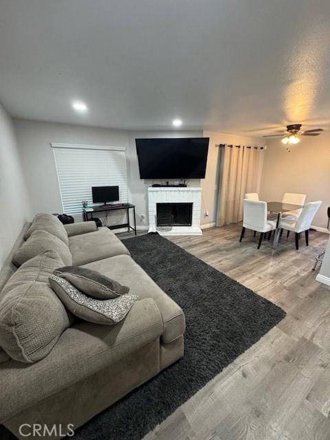 1025 N Tippecanoe Ave Unit 132, San Bernardino, CA 92410 - living area with a fireplace, a ceiling fan, and wood finished floors
