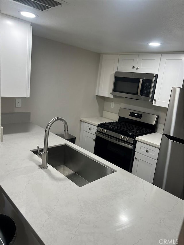 1025 N Tippecanoe Ave Unit 132, San Bernardino, CA 92410 - kitchen with stainless steel appliances, white cabinetry, recessed lighting, and light stone countertops
