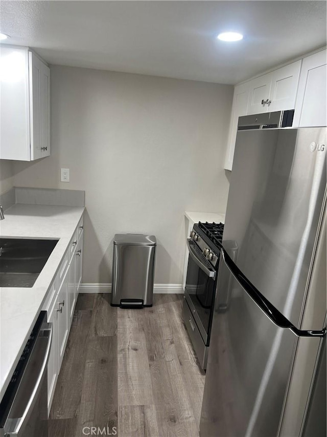 1025 N Tippecanoe Ave Unit 132, San Bernardino, CA 92410 - kitchen with appliances with stainless steel finishes, wood finished floors, white cabinets, light countertops, and recessed lighting
