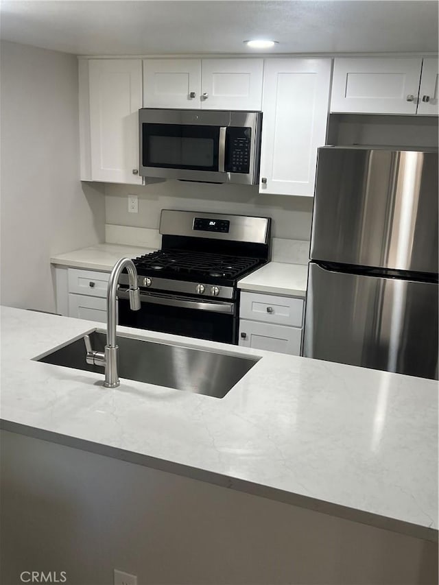 1025 N Tippecanoe Ave Unit 132, San Bernardino, CA 92410 - kitchen with appliances with stainless steel finishes, white cabinetry, and light stone countertops
