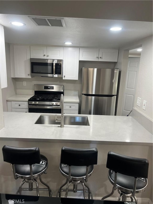 1025 N Tippecanoe Ave Unit 132, San Bernardino, CA 92410 - kitchen with appliances with stainless steel finishes, a kitchen breakfast bar, white cabinetry, light countertops, and recessed lighting