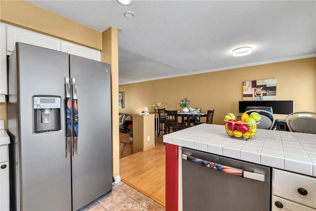 565 N Pageant Dr Unit B, Orange, CA 92869 - kitchen featuring appliances with stainless steel finishes, tile countertops, white cabinetry, crown molding, and light tile patterned floors