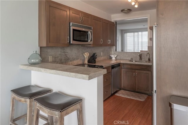 901 Ocean Ave, Santa Monica, CA 90403 - kitchen with appliances with stainless steel finishes, a kitchen bar, a peninsula, light wood finished floors, and tasteful backsplash