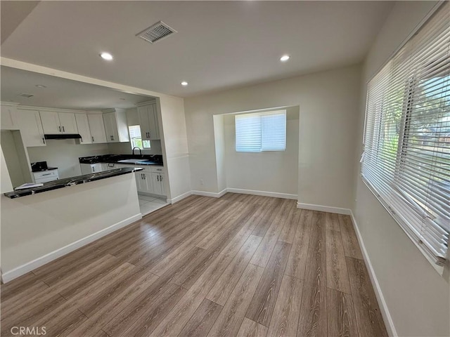 236 S 5th St, Montebello, CA 90640 - kitchen featuring under cabinet range hood, light wood finished floors, white cabinetry, dark countertops, and stove
