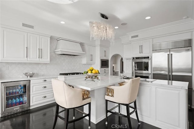 17 Lemans, Newport Coast, CA 92657 - kitchen with wine cooler, custom range hood, built in appliances, ornamental molding, and arched walkways