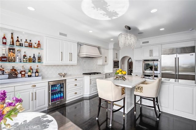 17 Lemans, Newport Coast, CA 92657 - kitchen featuring wine cooler, built in appliances, custom exhaust hood, arched walkways, and a chandelier