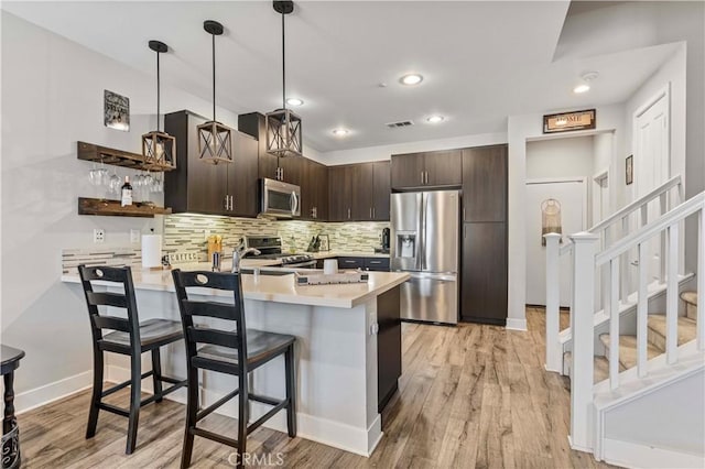 6 Fenix St, Rancho Mission Viejo, CA 92694 - kitchen with stainless steel appliances, a peninsula, dark brown cabinetry, light countertops, and a breakfast bar